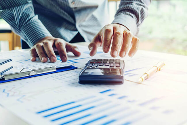 les mains d'un homme faisant des calculs sur une calculatrice
